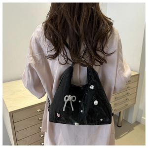 Detail of black pleated tote bag with rhinestone bow, pearls, and pink heart gem decoration