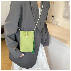 Détail du sac de téléphone vert menthe avec bouton perle et pompon élégant sur le côté