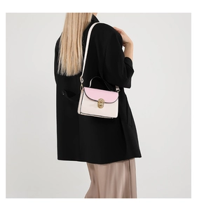 Detail of pink and cream contrast crossbody bag with gold turn-lock on a black blazer