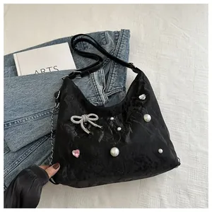 Detail of black pleated hobo bag with pearl accents, rhinestone bow and pink heart gem