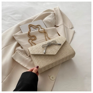 Gros plan du sac tissé beige avec boucle bijou papillon et chaîne dorée élégante