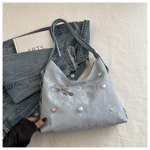 Detail of light blue tote bag with pearl accents, rhinestone bow, and heart gemstone