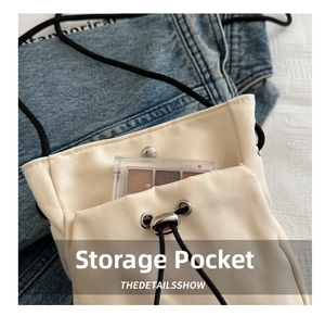 Detail van gebroken witte nylon crossbodytas met extern vak en handige trekkoordsluiting