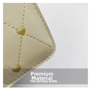 Detailed macro view of cream leather surface with diamond quilting and gold heart stitching