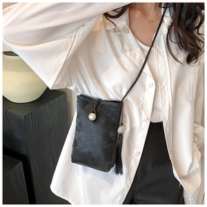 Detail of black vintage mini crossbody bag with embossed texture and pearl clasp