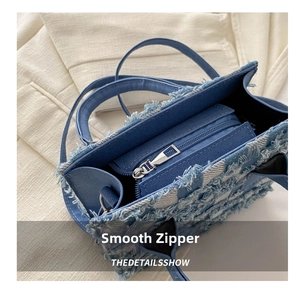 Detail der blauen Denim-Handtasche mit Patchwork-Muster und silbernem Reißverschluss