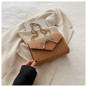 Détail du sac à main tissé en paille avec chaîne dorée et boucle papillon en cristal