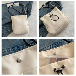 Detail van de crèmekleurige nylon mini crossbodytas met zilveren magneetsluiting en koord