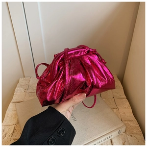 Detail view of metallic pink pleated shell bag with smooth texture and thin shoulder strap