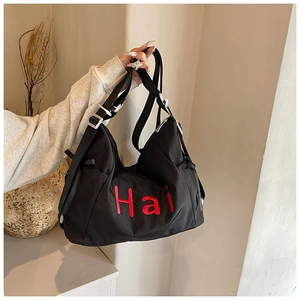 Detail of red Hai embroidery on a large black nylon bag with adjustable metal buckle