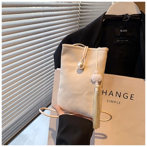 Dettaglio di una mini borsa beige a tracolla con fibbia a perla e nappa in seta