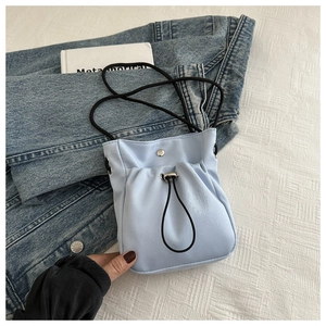 Detail of light blue nylon phone bag with black drawstring and magnetic closure strap