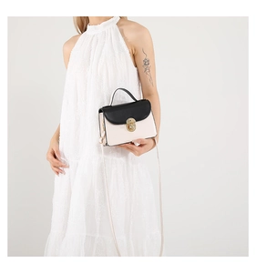 On-body view of a stylish black and white contrast mini square bag with gold twist lock