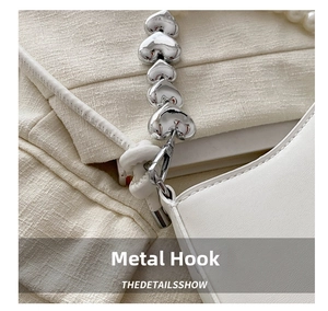 Detailed close-up of pearl shoulder strap with silver heart charms and metal hook