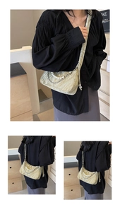 Détail du sac bandoulière plissé crème avec chaîne en perles et accents métalliques