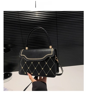 Detail of black crossbody bag with golden heart studs and wavy braided flap edges