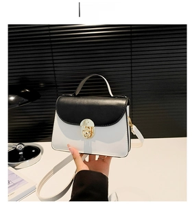 Detail of elegant black and white contrast small square bag with round gold metal lock