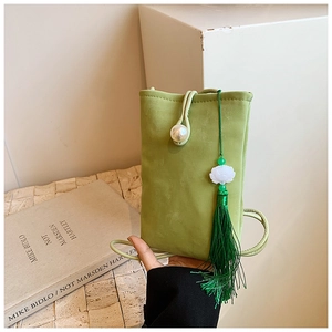 Dettaglio borsa porta cellulare verde scamosciata con bottone di perla e nappa