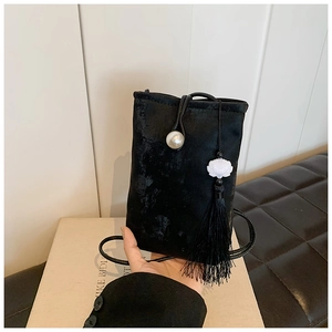 Dettaglio della borsa porta cellulare in velluto nero con perla, ciondolo loto e nappa