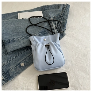 Close-up of light blue canvas phone bag with drawstring detail and black rope strap