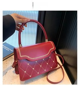 Detail of red quilted heart pattern and gold wavy embroidery on fashionable PU leather bag