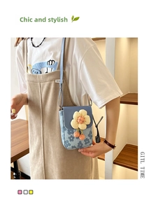 Petit sac bandoulière à fleurs bleues avec fleur jaune porté sur une robe beige