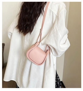 Vista dettagliata di una mini borsa a tracolla rosa indossata con camicia e gonna a fiori