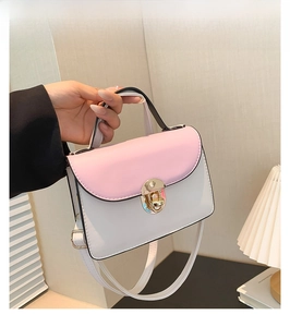 Detail of pink and white patchwork handbag with golden clasp and metal handle accessory