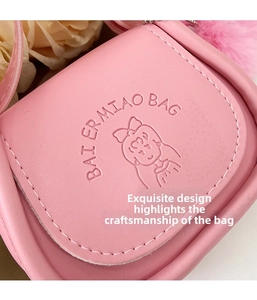 Détail du sac en cuir rose avec illustration de fille et breloque boule de poils