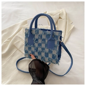 Detailansicht der karierten Handtasche mit modischen Fransen und robustem Stoffgriff