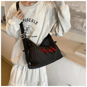 Close-up of black nylon tote bag featuring red Hai letter embroidery and adjustable strap