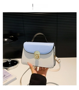 Detail view of stylish blue and white color-block handbag with gold metallic buckle