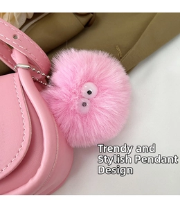 Gros plan d'un charme en peluche rose avec des yeux mobiles sur un sac à main en cuir
