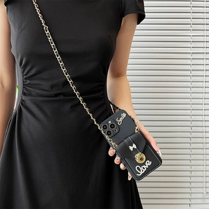 Detail of iPhone wallet case with metal bow, crossbody chain, and diamond letters