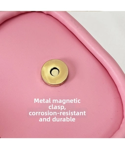 Vue macro du fermoir magnétique doré sur le cuir grainé rose du sac besace