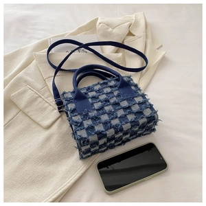 Detail der blau-weiß karierten Handtasche mit Fransenbesatz und Denim-Textur