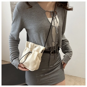 Detail van de crèmewitte crossbodytas met trekkoord en zwart koord bij het model