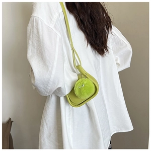 Détail du sac selle vert citron avec charm peluche œil mignon sur une finition mate