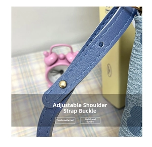 Détail de la bandoulière en cuir bleu réglable avec boucle en métal doré pour le sac