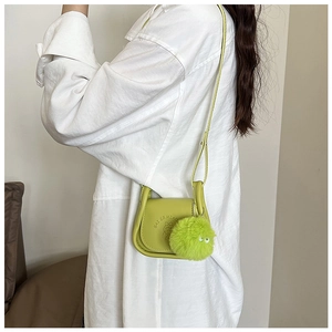 Détail du sac bandoulière vert avocat avec logo gaufré et pendentif en forme de boule