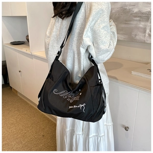 Detail of black nylon tote with white embroidery and stars on a casual shoulder bag