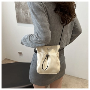 Achteraanzicht van model met een minimalistische beige crossbody tas met trekkoord detail