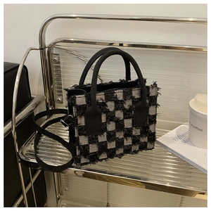 Detail der gewebten Tasche im Schachbrettmuster mit Fransen auf modernem Ständer