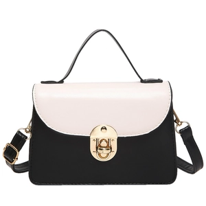 Minimalist black and white patchwork handbag with gold circular lock and crossbody strap