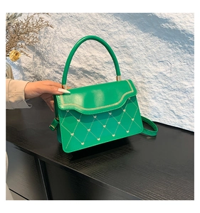 Detail of green handbag with heart-shaped quilted pattern and wave edge stitching