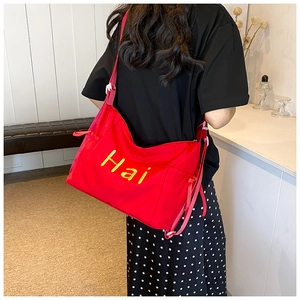Close-up of red canvas bag with yellow lettering and adjustable shoulder strap