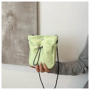 Close-up of mint green canvas phone bag with drawstring pocket and black strap