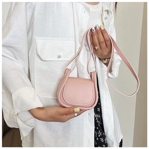 Vista dettagliata di una mini borsa a sella rosa con tracolla tenuta da una modella