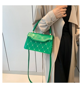 Detail of green quilted crossbody bag with golden heart studs and chain edge trim