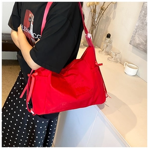 Detail of red nylon crossbody bag featuring stylish side ties and embroidered lettering